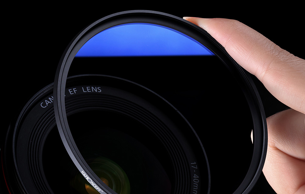 Sinine optiline filter käes, kaamera objektiiv taustal